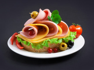 Sandwich with boiled sausage, greens and cheese on a white plate