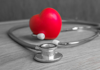 Red heart and stethoscope on wooden background.