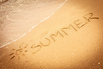 The word summer written in the sand on a beach