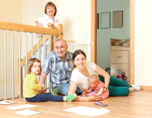 Happy couple with their offspring and grandmother on floor at ho