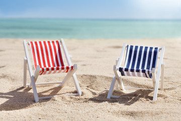 Two Deckchairs On Beach