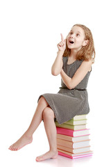 cheerful girl sitting on the books and showing thumb up