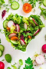 Healthy salad with fresh vegetables and ingredients on white bac