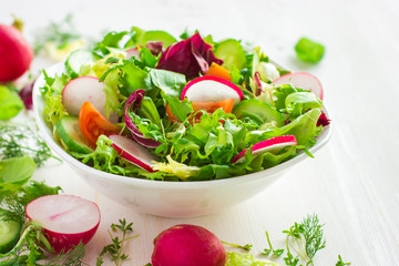Healthy salad with fresh vegetables and ingredients on white bac
