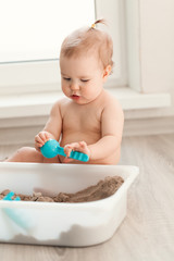Little girl playing with sand on floor