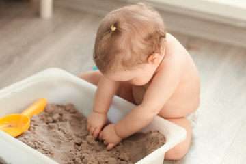 Little girl playing with sand on floor