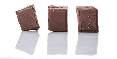 Dark brown chocolate pieces over white background