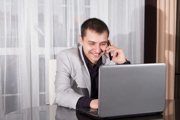 Businessman using a laptop and speaks on mobile phone
