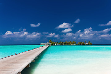 Wooden jetty to a tropical island over lagoon in Maldives