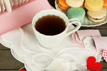 Obraz na płótnie Canvas Heart shaped teabag tags, macaroons and cup of tea