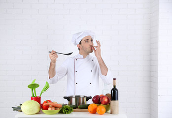 Chef at table with different products and utensil in kitchen on white wall background