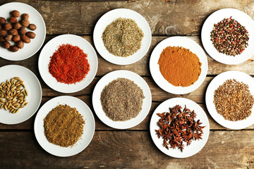 Different spices on plates, on old wooden table