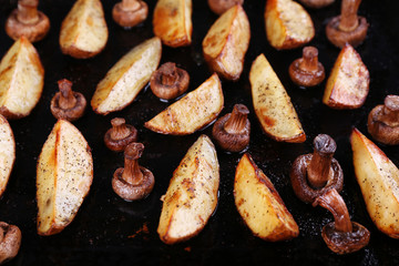 Baked potatoes with mushrooms and spices on pan close up