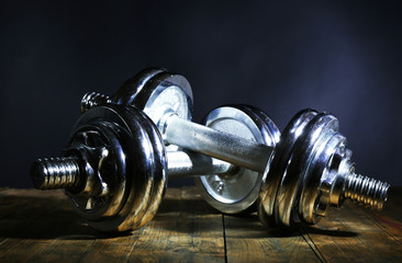 Dumbbells on wooden board, on dark background