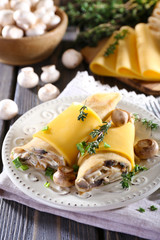 Pancakes with creamy mushrooms in plate on wooden table,
