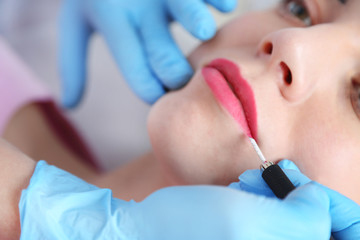 Cosmetologist applying permanent make up on lips