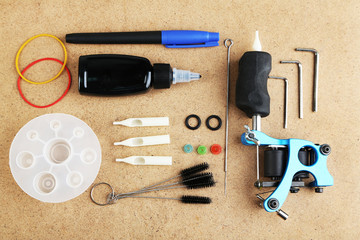 Tattoo machine and tattoo Supplies, on wooden background