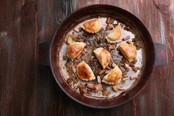 Fried dumplings with onion and bacon in frying pan,