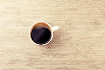 Cup of coffee on wooden table, top view