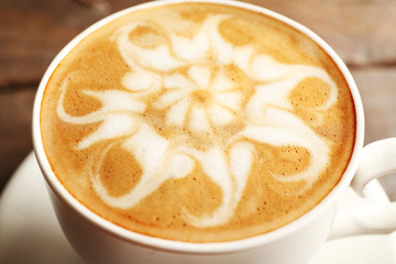 Cup of coffee latte art on wooden table, closeup