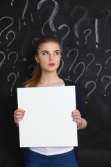 Young girl with question mark holding a blank on  gray