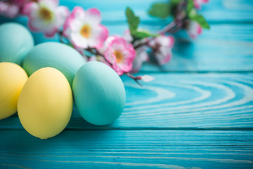 easter colored eggs with lace ribbon and flowers on blue wooden
