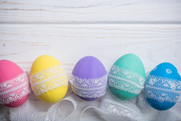 easter eggs with lace ribbon on white wooden background