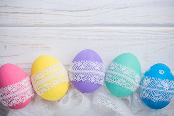 easter eggs with lace ribbon on white wooden background