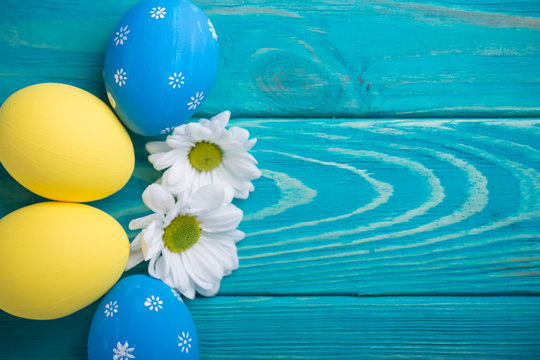 easter colored eggs with lace ribbon and flowers on blue wooden