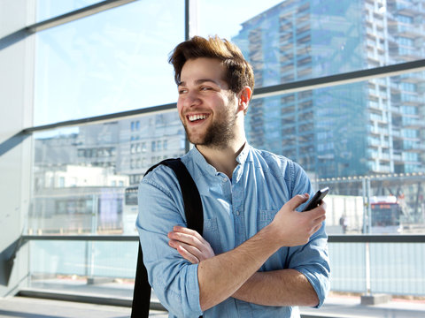 Cheerful Young Man Standing At Station With Mobile Phone