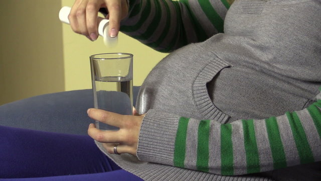 Pregnant woman put pill of lemon taste to water glass