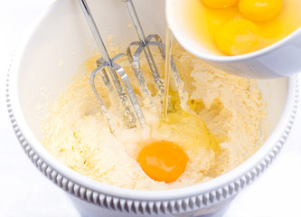 Concept of homemade bakery, pouring eggs to the dough in mixing