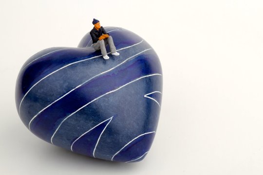 miniatura di uomo solitario su un cuore