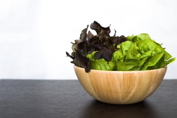 Two (2) tone salad in wooden bowl on dark wood table isolated on