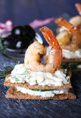 Appetizer canape with shrimp and olives on plate close up