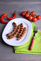 Grilled sausages on plate with vegetables on table close up