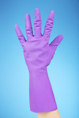 Rubber glove on hand, on blue background