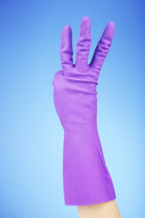 Rubber glove on hand, on blue background