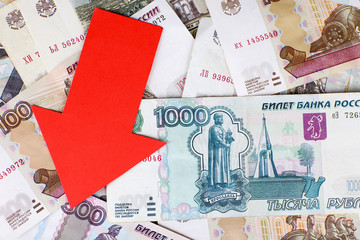 Red arrow on Russian money as depreciation of currency, closeup