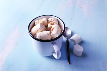 Mug of cocoa with marshmallows on wooden table background