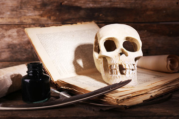 Still life with human skull, retro book and quill