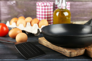 Still life with eggs and pan on wooden background