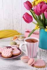 Composition of spring flowers, tea and cookies on table