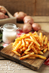 Tasty french fries on cutting board, on wooden table background © Africa Studio