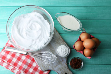 Whipped egg whites for cream on wooden table, top view