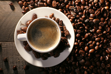 Cup of coffee with grains on wooden table, top view