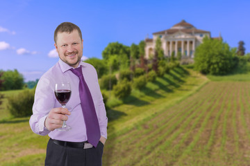 Businessman holding glass of wine with beautiful villa in