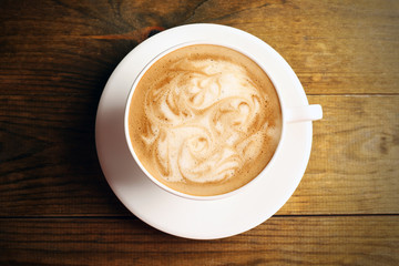 Cup of coffee latte art on wooden table, top view