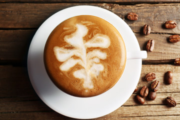 Cup of coffee latte art with grains on wooden table, top view