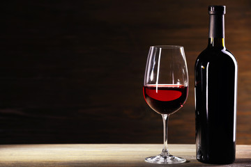 Fototapeta na wymiar Wineglass and bottle on wooden background